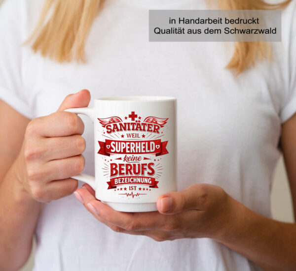 Frau Trinkt Aus Einer Schoener Weissen Keramik Tasse Mit Dem Spruch Sanitaeter Weil Superheld Keine Berufsbezeichnung Ist