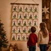 Adventskalender Mit 24 Baumwollsaeckchen Zum Befuellen Auf Festlicher Weihnachtskulisse. Lustige Monste Motive Mit Weihnachtsmuetze Und Humorvollen Spruechen An Der Wand