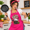 Fotorealistische Frau Mit Pinker Kochschuerze ‚Chefin Der Pfanne‘ Beim Kochen In Einer Modernen Kueche Mit Schwarzer Bratpfanne In Der Hand – Lustige Kuechenschuerze Fuer Hobbykoeche